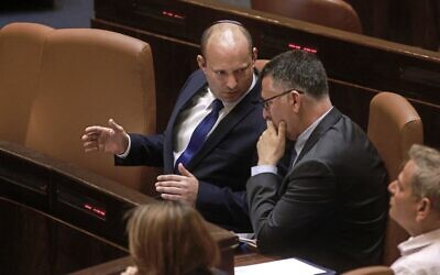 Prime Minister Naftali Bennett (left) speaks with Justice Minister Gideon Sa'ar in the Knesset on June 16, 2021. (Menahem Kahana / AFP)