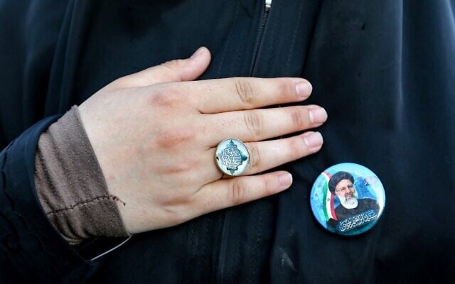 A woman holds her hand to her chest next to a pin bearing the image of Iran's newly-elected president Ebrahim Raisi during a rally celebrating his victory in Imam Hussein square in the capital Tehran on June 19, 2021. (ATTA KENARE / AFP)