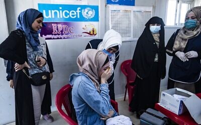 A woman receives a shot of a COVID-19 vaccine in the Kurdish-run al-Hol camp in Hasakeh governorate in northeastern Syria, on June 23, 2021. (Delil Souleiman/AFP)