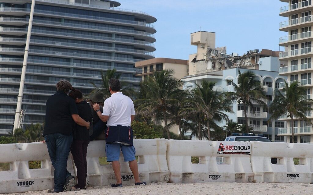 People stand together as they look on at the 12-story Champlain Towers South condo building that partially collapsed on June 26, 2021 in Surfside, Florida (JOE RAEDLE / GETTY IMAGES NORTH AMERICA / Getty Images via AFP)