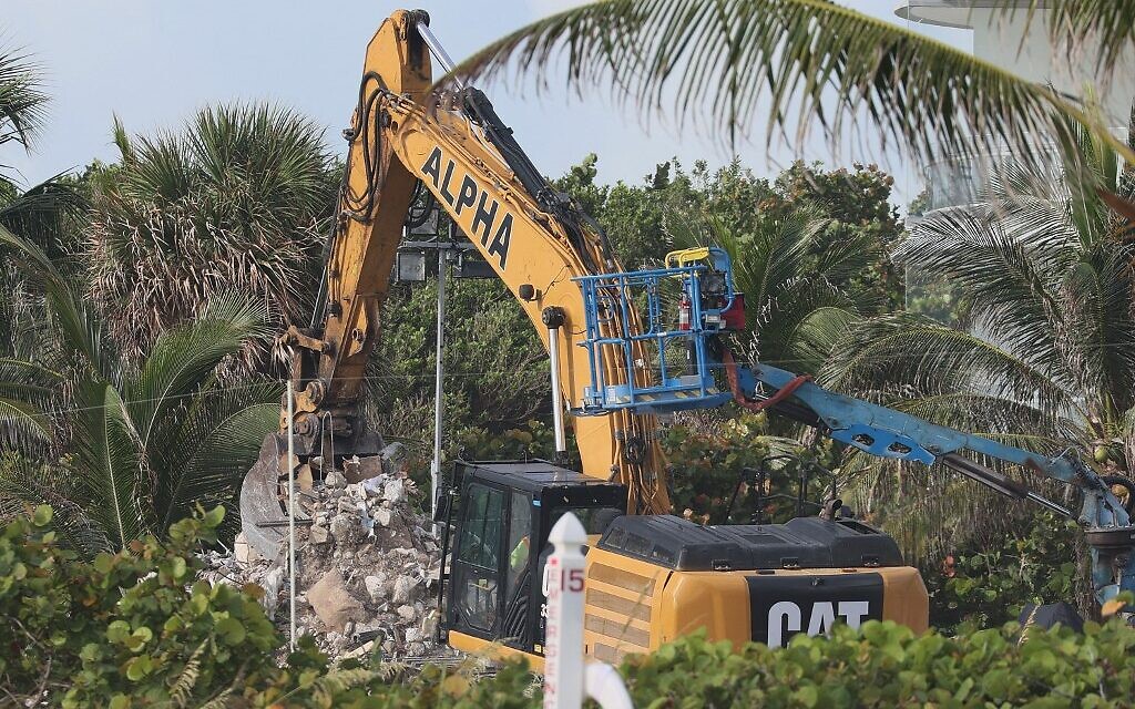 An excavator is used to move debris as search and rescue personnel work to find any survivors or casualties in the partially collapsed 12-story Champlain Towers South condo building on June 26, 2021 in Surfside, Florida (JOE RAEDLE / GETTY IMAGES NORTH AMERICA / Getty Images via AFP)