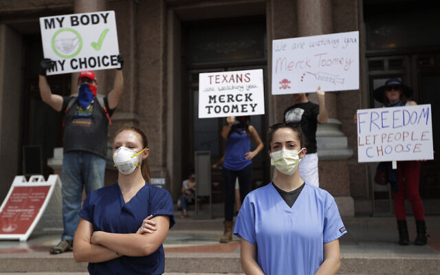 Health care workers wearing scrubs and face masks watch as protesters hold an "Open Texas" rally at the Texas State Capitol, Saturday, April 25, 2020, in Austin, Texas. (AP Photo/Eric Gay) Health care workers wearing scrubs and face masks watch as protesters hold an "Open Texas" rally at the Texas State Capitol, Saturday, April 25, 2020, in Austin, Texas. (AP Photo/Eric Gay)