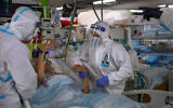 Medical personnel wearing protective equipment treat a COVID-19 patient in an intensive care ward that has been converted from underground parking, at Rambam Hospital in the northern Israeli city of Haifa, December 15, 2020. (AP Photo/Oded Balilty)