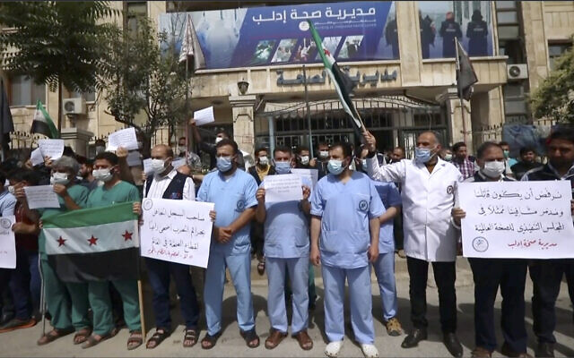 In this image taken from video, dozens of medical workers protest a decision to grant Syrian President Bashar Assad’s government a seat on the executive board of the World Health Organization, Monday, May 31, 2021, in Idlib, Syria.  (AP)