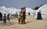 In this March 29, 2021, file photo, a woman holds a baby at Karatepe refugee camp, on the eastern Aegean island of Lesbos, Greece. (AP Photo/Panagiotis Balaskas, File)