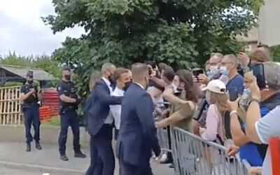 In this grab taken from video France's President Emmanuel Macron, center, is slapped by a man, in green T-shirt, during a visit to Tain-l’Hermitage, in France on June 8, 2021. (BFM TV via AP)