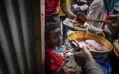 Elena, 7, center, lines up with other displaced Tigrayans to receive food donated by local residents at a reception center for the internally displaced in Mekele, in the Tigray region of northern Ethiopia, on May 9, 2021 (AP Photo/Ben Curtis)