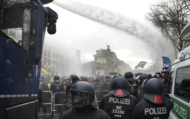 In this file photo, police use water canons to clear a blocked road near the German federal parliament, as people attend a protest rally in Berlin, Germany, against the coronavirus restrictions in Germany in July 2020. (AP Photo/Michael Sohn, file) In this file photo, police use water canons to clear a blocked road near the German federal parliament, as people attend a protest rally in Berlin, Germany, against the coronavirus restrictions in Germany in July 2020. (AP Photo/Michael Sohn, file)