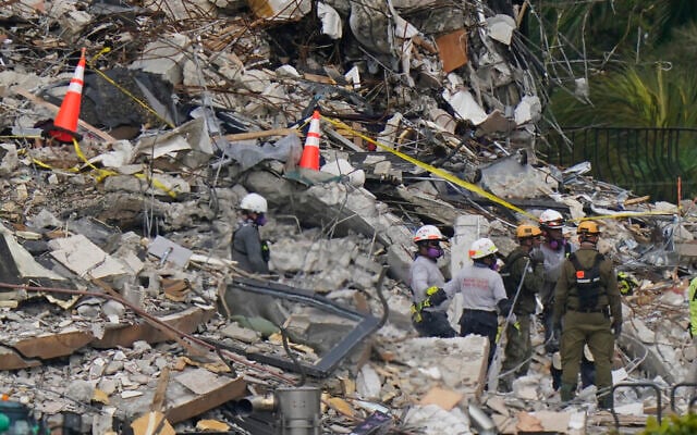 Local search and rescue personnel talk with members of an Israeli team, as they work atop the rubble at the Champlain Towers South condo building where scores of people remain missing almost a week after it partially collapsed, June 30, 2021, in Surfside, Florida. (AP Photo/Lynne Sladky) Local search and rescue personnel talk with members of an Israeli team, as they work atop the rubble at the Champlain Towers South condo building where scores of people remain missing almost a week after it partially collapsed, June 30, 2021, in Surfside, Florida. (AP Photo/Lynne Sladky)