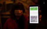 Illustrative image: A woman shows her green pass as she arrives to watch a play at the Khan theater in Jerusalem, on February 23, 2021. (Yonatan Sindel/Flash90)
