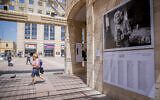 People walk past a photo exhibition of the last survivors of the Holocaust as part of the 'Lonka project,' at Safra Square in Jerusalem, April 8, 2021. (Yonatan Sindel/Flash90)