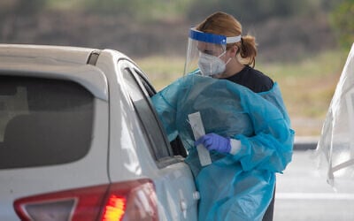 Illustrative: A healthcare worker takes swab samples from Israelis at a coronavirus drive-thru testing station in the central city of Ramle on April 18, 2021. (Yossi Aloni/Flash90)