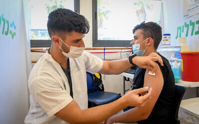 A young Israeli receives a coronavirus vaccine shot at a Clalit vaccination center in Petah Tikva on June 6, 2021. (Flash90)
