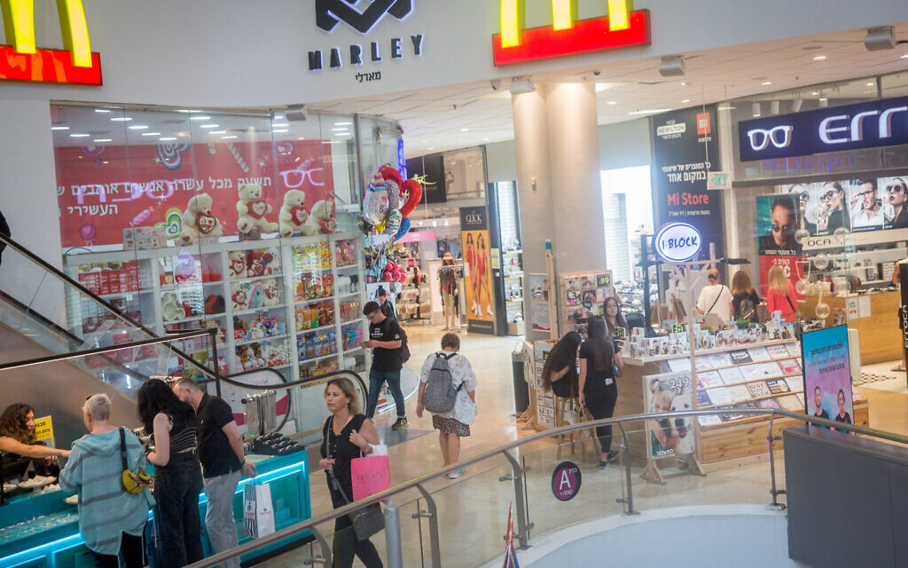 People shop at the Dizengoff Center mall in Tel Aviv on June 14, 2021, after the Health Ministry announced the end of the COVID-19 obligation to wear a mask in closed public places. (Miriam Alster/Flash90)