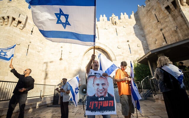 An Israeli man waving a flag holds a poster calling Prime Minister Naftali Bennett 'the liar,' during the nationalist flag march, at the Damascus Gate in Jerusalem's Old City, June 15, 2021. (Yonatan Sindel/Flash90) An Israeli man waving a flag holds a poster calling Prime Minister Naftali Bennett 'the liar,' during the nationalist flag march, at the Damascus Gate in Jerusalem's Old City, June 15, 2021. (Yonatan Sindel/Flash90)
