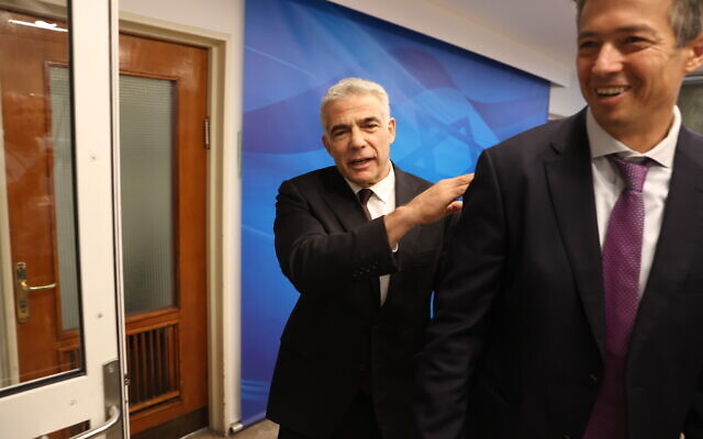 Foreign Minister Yair Lapid (left) arrives for the first cabinet meeting of the new government at the Prime Minister's Office in Jerusalem on June 20, 2021. In foreground is Communications Minister Yoaz Hendel. (Amit Shabi/POOL)