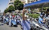Scooter drivers waiting outside a gas station in Lebanon's capital Beirut raise their middle fingers in protest against hikes in the price of fuel, June 29, 2021. (Joseph Eid/AFP)