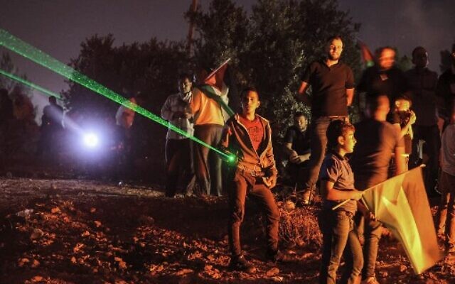Palestinian protesters use laser torches during a demonstration against the Israeli settlers' outpost of Evyatarin the West Bankon July 1, 2021. (Photo by JAAFAR ASHTIYEH / AFP) Palestinian protesters use laser torches during a demonstration against the Israeli settlers' outpost of Evyatarin the West Bankon July 1, 2021. (Photo by JAAFAR ASHTIYEH / AFP)