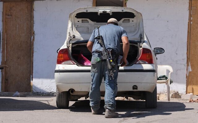An armed settler gathers belongings in his car before evacuating the newly-established wildcat outpost of Evyatar near the northern Palestinian city of Nablus in the West Bank, on July 2, 2021 (Emmanuel DUNAND / AFP)