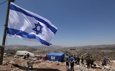 Israeli soldiers and settlers stare at the Palestinian village of Beita before evacuating the newly-established wildcat outpost of Evyatar near the northern Palestinian city of Nablus in the West Bank, on July 2, 2021 (Emmanuel DUNAND / AFP)