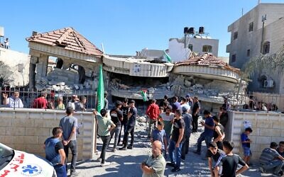 Palestinians gather outside a building that belonged to Muntasir Shalabi, accused of killing an Israeli student in a May terror attack, after it was demolished by Israeli forces in the village of Turmus Ayya near Ramallah in the West Bank on July 8, 2021 (JAAFAR ASHTIYEH / AFP)