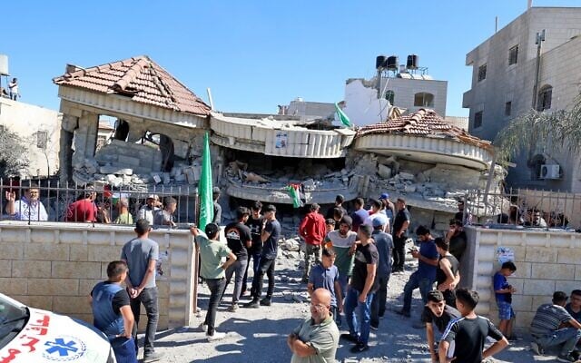 Palestinians gather outside a building that belonged to Muntasir Shalabi, accused of killing an Israeli student in a May terror attack, after it was demolished by Israeli forces in the village of Turmus Ayya near Ramallah in the West Bank on July 8, 2021 (JAAFAR ASHTIYEH / AFP) Palestinians gather outside a building that belonged to Muntasir Shalabi, accused of killing an Israeli student in a May terror attack, after it was demolished by Israeli forces in the village of Turmus Ayya near Ramallah in the West Bank on July 8, 2021 (JAAFAR ASHTIYEH / AFP)
