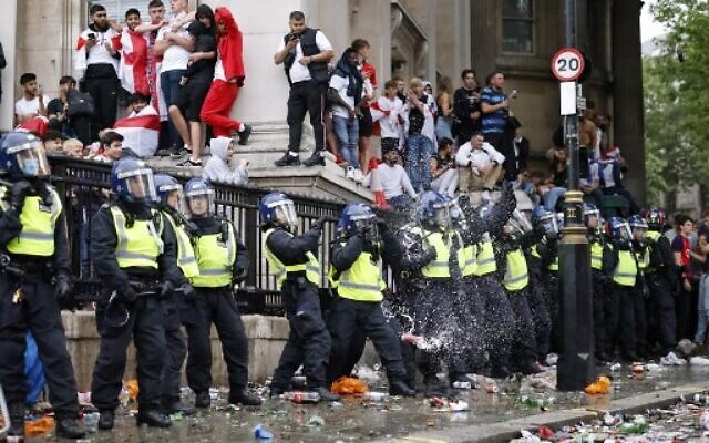 A line of police officers are the target of beer can throwers as England supporters stand around the edges of Trafalgar Square during a live screening of the UEFA EURO 2020 final soccer match between England and Italy in central London on July 11, 2021. (Photo by Tolga Akmen / AFP)