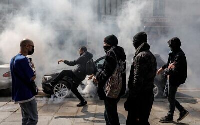 A demonstrator kicks back a gas canister to Police on the sidelines of a protest in central Paris on July 14, 2021 against a governmental decision to impose Covid-19 tests for unvaccinated people who want to eat in restaurants or take long-distance trips, as the country looks to avoid a surge in more contagious Delta cases. (GEOFFROY VAN DER HASSELT / AFP)