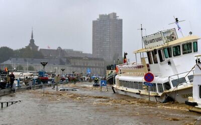 Members of the public stand next to a damaged boat after the floodings in Liege on July 15, 2021. (BERNARD GILLET / BELGA / AFP) / Belgium OUT