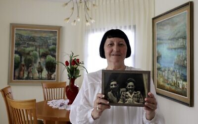 Shoshana Greenberg, 74, the daughter of a Holocaust survivor, poses for a picture holding a portrait of her parents Regina and Israel, at her home in Israeli city of Tel Aviv on July 18, 2021. (MENAHEM KAHANA / AFP)