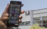 In this file photo taken on August 28, 2016, a woman uses her iPhone in front of the building housing the Israeli NSO group, in Herzliya, near Tel Aviv. (Jack Guez/AFP)