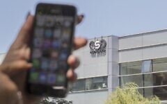 In this file photo taken on August 28, 2016, a woman uses her iPhone in front of the building housing the Israeli NSO group, in Herzliya, near Tel Aviv. (Jack Guez/AFP)