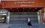 Iranians walk past a shuttered cinema hall in downtown Tehran on July 20, 2021. (ATTA KENARE / AFP)