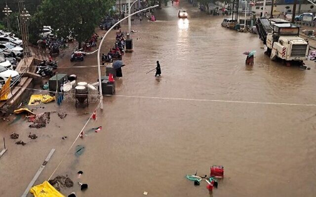 This photo taken on July 20, 2021 shows people wading through flood waters along a street following heavy rains in Zhengzhou in China's central Henan province. (Photo by STR / AFP) This photo taken on July 20, 2021 shows people wading through flood waters along a street following heavy rains in Zhengzhou in China's central Henan province. (Photo by STR / AFP)