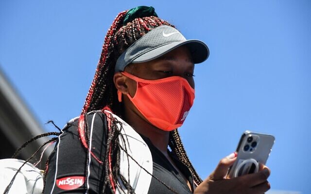 Japan's Naomi Osaka looks at her phone at Ariake Tennis Park ahead of the Tokyo 2020 Olympic Games in Tokyo on July 23, 2021. (Tiziana FABI / AFP)
