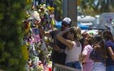 People observe the memorial to those missing outside the 12-story Champlain Towers South condo building that partially collapsed on July 4, 2021 in Surfside, Florida. (Saul MARTINEZ / Getty Images via AFP)