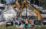 Rescue workers watch as excavators are used to dig through the rubble of the collapsed 12-story Champlain Towers South condo building on July 9, 2021 in Surfside, Florida. (Anna Moneymaker / Getty Images North America / Getty Images via AFP)