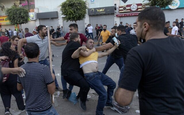 Palestinian security officers in plainclothes detain a demonstrator during clashes that erupted following a rally protesting the death of outspoken PA critic Nizar Banat, in the West Bank city of Ramallah, on Saturday, June 26, 2021. (AP Photo/Nasser Nasser)