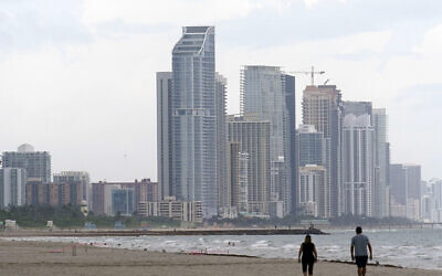 A couple walk on the beach, June 29, 2021, in Surfside, Florida. (AP Photo/Marta Lavandier)