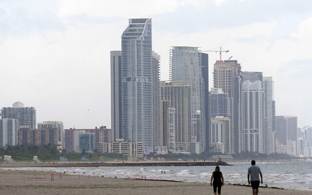 A couple walk on the beach, June 29, 2021, in Surfside, Florida. (AP Photo/Marta Lavandier)