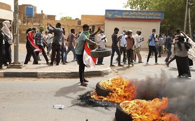 A demonstrator throws a tire on a fire during a protest over economic conditions, in Khartoum, Sudan, Wednesday, June 30, 2021. (AP Photo/Marwan Ali)