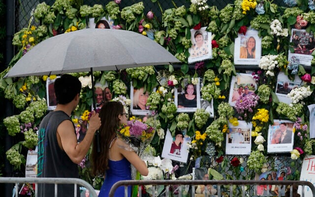Visitors bring flowers to add to a makeshift memorial for the scores of people who were left missing after the Champlain Towers South condo building partially collapsed nearly a week ago, Wednesday, June 30, 2021, in Surfside, Fla.. (AP Photo/Gerald Herbert) Visitors bring flowers to add to a makeshift memorial for the scores of people who were left missing after the Champlain Towers South condo building partially collapsed nearly a week ago, Wednesday, June 30, 2021, in Surfside, Fla.. (AP Photo/Gerald Herbert)