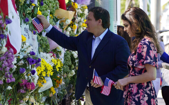 Florida Gov. Ron DeSantis, left, and his wife Casey leave flags at a makeshift memorial near the Champlain Towers South condo building, where scores of victims remain missing more than a week after it partially collapsed, Saturday, July 3, 2021, in Surfside, Fla. (AP Photo/Lynne Sladky) Florida Gov. Ron DeSantis, left, and his wife Casey leave flags at a makeshift memorial near the Champlain Towers South condo building, where scores of victims remain missing more than a week after it partially collapsed, Saturday, July 3, 2021, in Surfside, Fla. (AP Photo/Lynne Sladky)