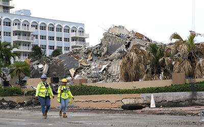 Workers walk past the collapsed and subsequently demolished Champlain Towers South condominium building, Tuesday, July 6, 2021, in Surfside, Fla. (AP Photo/Lynne Sladky)