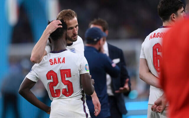 England's Harry Kane, center, consoles Bukayo Saka after the penalty shootout of the Euro 2020 soccer final match between England and Italy at Wembley stadium in London, July 11, 2021. (Laurence Griffiths/Pool via AP) England's Harry Kane, center, consoles Bukayo Saka after the penalty shootout of the Euro 2020 soccer final match between England and Italy at Wembley stadium in London, July 11, 2021. (Laurence Griffiths/Pool via AP)