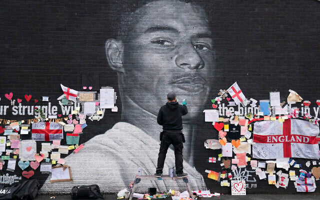Street artist Akse P19 repairs the mural of Manchester United striker and England player Marcus Rashford on the wall of the Coffee House Cafe on Copson Street, in Withington, Manchester, England, July 13, 2021. (AP/Jon Super) Street artist Akse P19 repairs the mural of Manchester United striker and England player Marcus Rashford on the wall of the Coffee House Cafe on Copson Street, in Withington, Manchester, England, July 13, 2021. (AP/Jon Super)