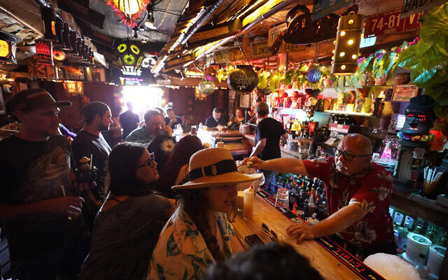 In this Wednesday, July 7, 2021, file photo, patrons enjoy cold tropical cocktails in the tiny interior of the Tiki-Ti bar as it reopens on Sunset Boulevard in Los Angeles. COVID-19 cases have doubled over the past three weeks, driven by the fast-spreading delta variant, lagging vaccination rates in some states and Fourth of July gatherings. Los Angeles County public health officials have urged people to resume wearing masks indoors regardless of their vaccination status. (AP Photo/Damian Dovarganes, File) In this Wednesday, July 7, 2021, file photo, patrons enjoy cold tropical cocktails in the tiny interior of the Tiki-Ti bar as it reopens on Sunset Boulevard in Los Angeles. COVID-19 cases have doubled over the past three weeks, driven by the fast-spreading delta variant, lagging vaccination rates in some states and Fourth of July gatherings. Los Angeles County public health officials have urged people to resume wearing masks indoors regardless of their vaccination status. (AP Photo/Damian Dovarganes, File)