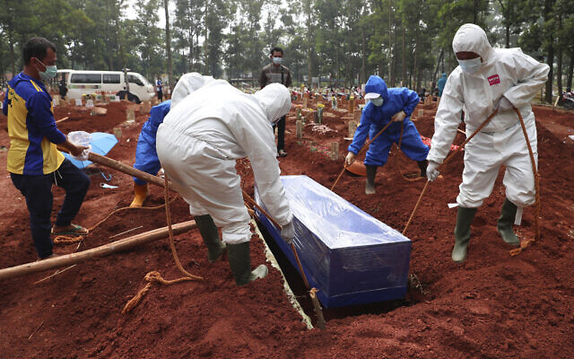 Workers in protective gear lower a coffin of a COVID-19 victim to a grave for burial at the Cipenjo Cemetery in Bogor, West Java, Indonesia, July 14, 2021. (Achmad Ibrahim/AP) Workers in protective gear lower a coffin of a COVID-19 victim to a grave for burial at the Cipenjo Cemetery in Bogor, West Java, Indonesia, July 14, 2021. (Achmad Ibrahim/AP)