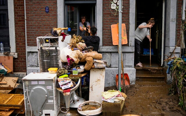 People pass damaged belongings out of a house after flooding in Ensival, Verviers, Belgium, July 16, 2021 (AP Photo/Francisco Seco)
