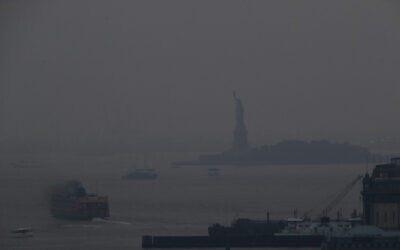 The Staten Island Ferry departs from the Manhattan terminal through a haze of smoke with the Statue of Liberty barely visible, on Tuesday, July 20, 2021, in New York. (AP Photo/Julie Jacobson)